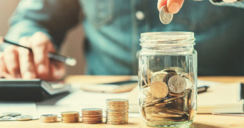 Cómo recortar gastos en época de crisis persona poniendo monedas en un frasco para ahorrar dinero