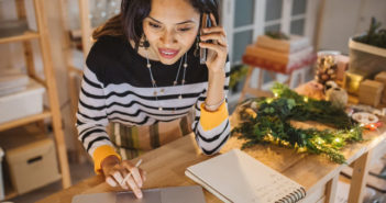 Cómo prepararse para la temporada de compras navideñas Mujer empresaria llamando por teléfono junto a adornos navideños