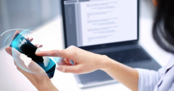Ventajas de tener una oficina virtual para operar un negocio en casa Mujer usando su telefono frente a una laptop
