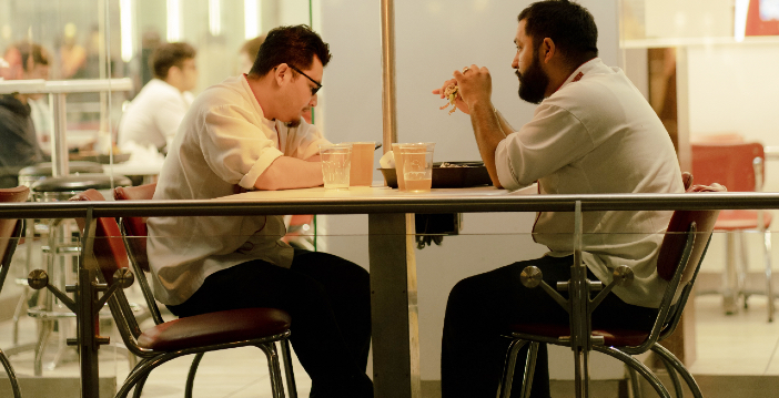 dos hombres comiendo en una mesa al aire libre