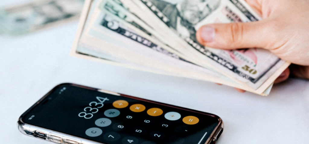 mano con dolares junto a una calculadora